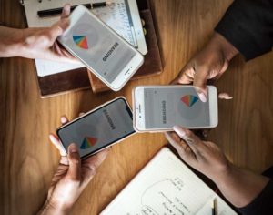 What Are QA Test Cases (picture depicts two peoples' hands, white and black, holding iPhones with generic graphs on them)