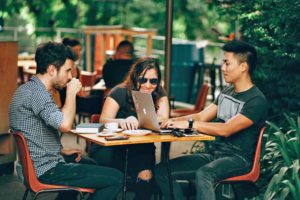 Tech Diversity (picture depicts a woman and two men sitting at an outdoor table at a coffee shop)