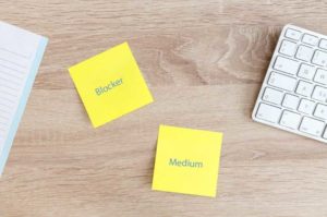 How to Prioritize Bug Fixes (image shows a wood desk with yellow post-its and a keyboard)