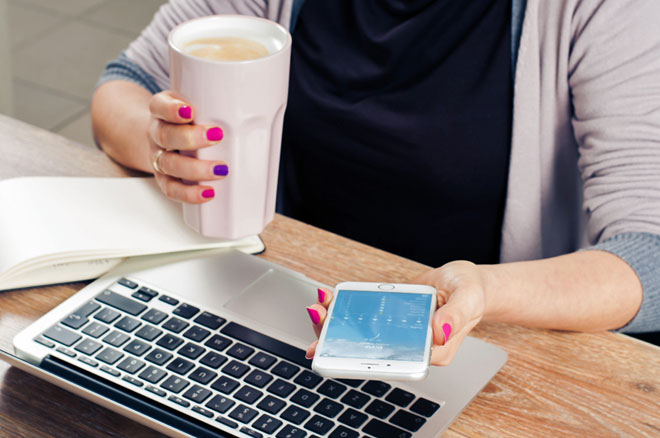 User Experience: image depicts person's arms, one (with pink and purple nail polish) holding a beverage, and the other holding a phone with an app open