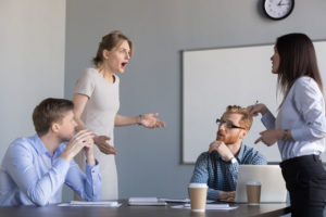 Blaming Developers (picture depicts an office meeting room with four different people appearing to be arguing)