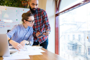 Developer Communication (picture depicts two programmers discussing information in an office)