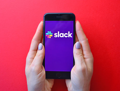 Slack Workplace Boundaries (two hands holding a mobile phone with the Slack app open)